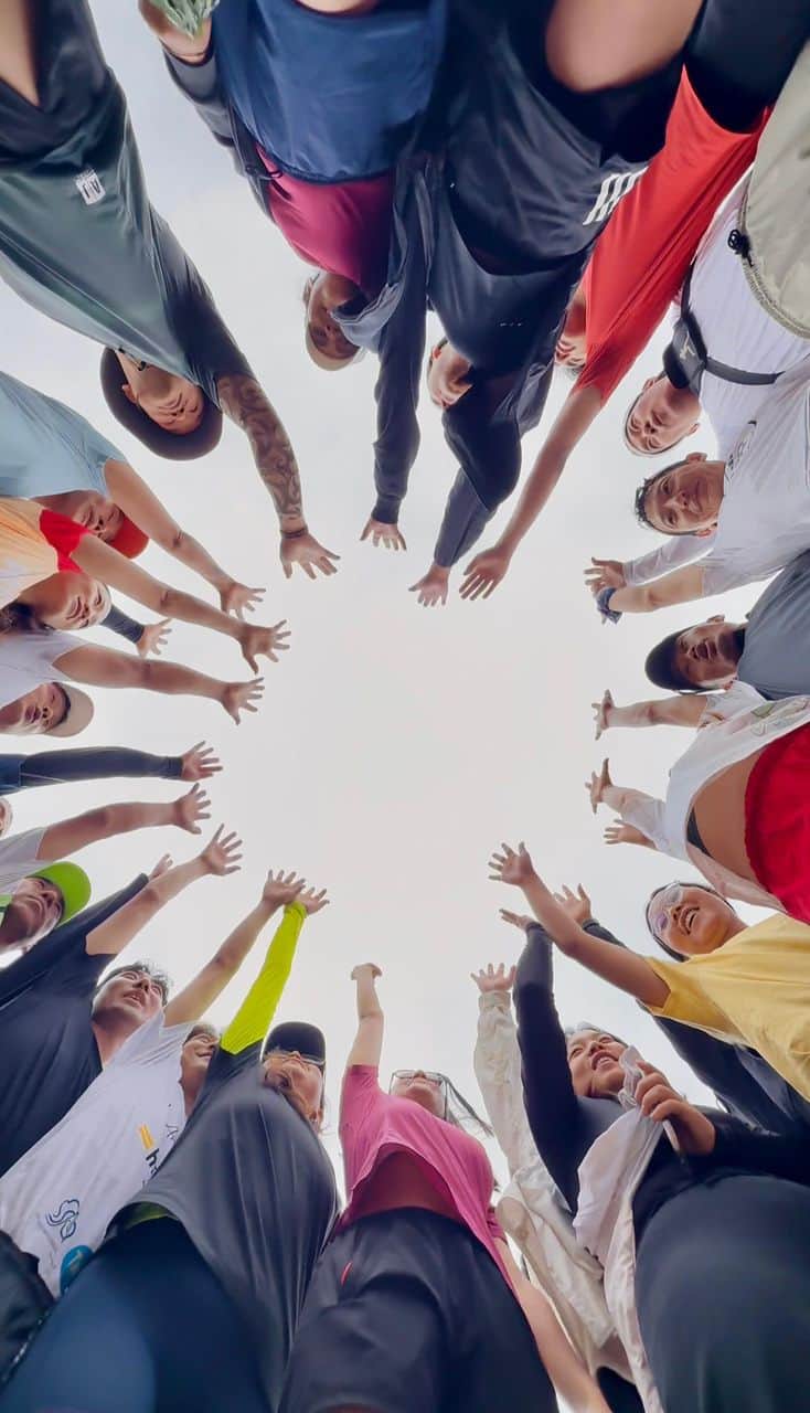 The MountaiNation community in a huddle, hands raised together
